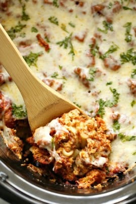 Lasagna in the slow cooker being dished out with wooden spoon