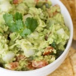 A white bowl full of Easy Guacamole surrounded by chips.