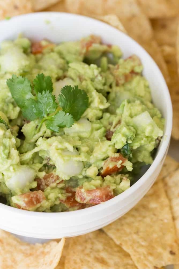 A white bowl full of Easy Guacamole surrounded by chips.