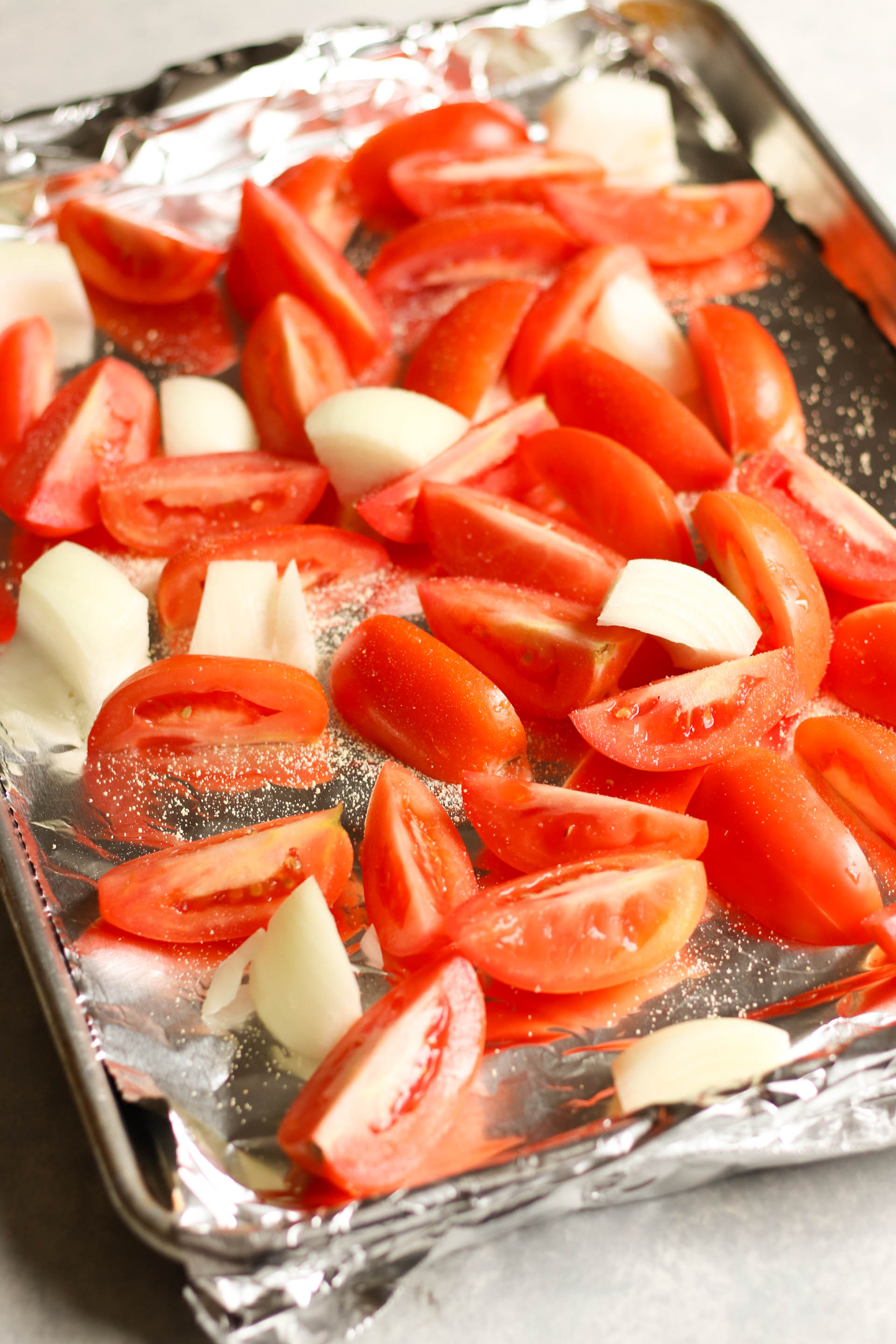 tomatoes and onions sliced on a baking sheet