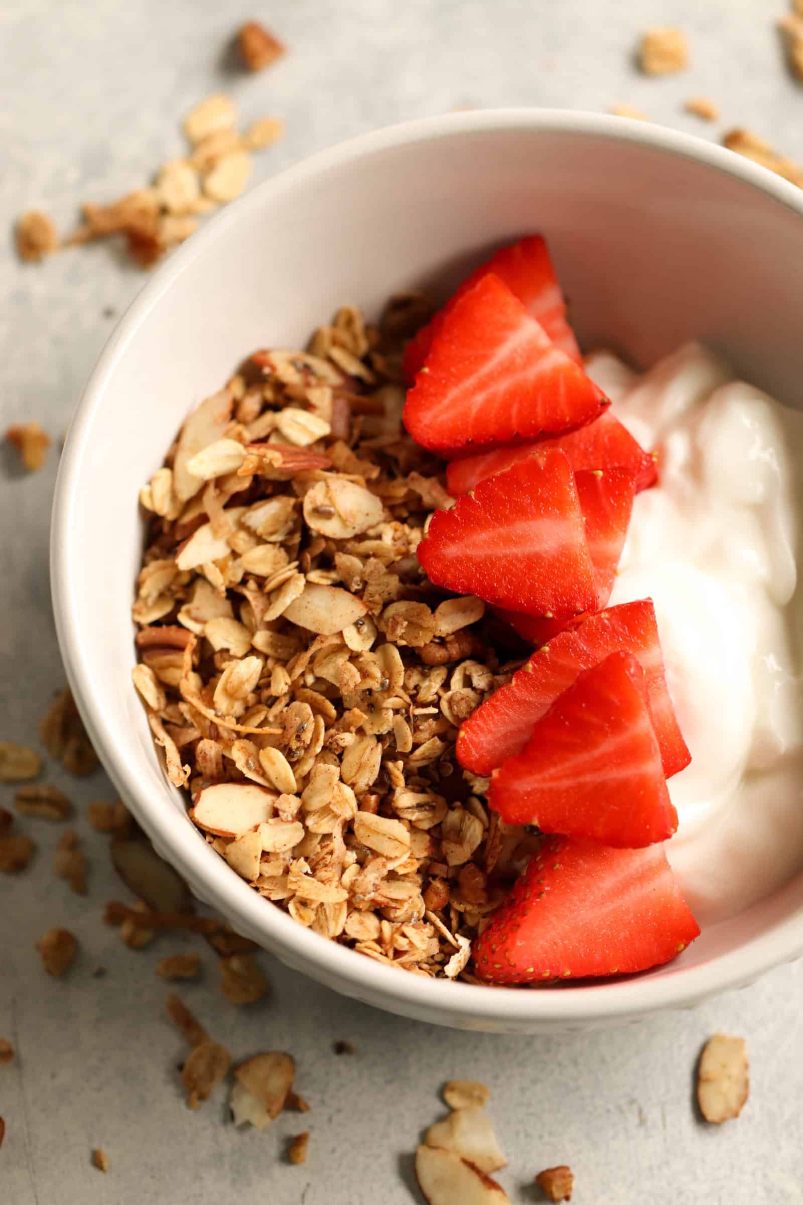 A bowl of yogurt with granola and sliced strawberries.
