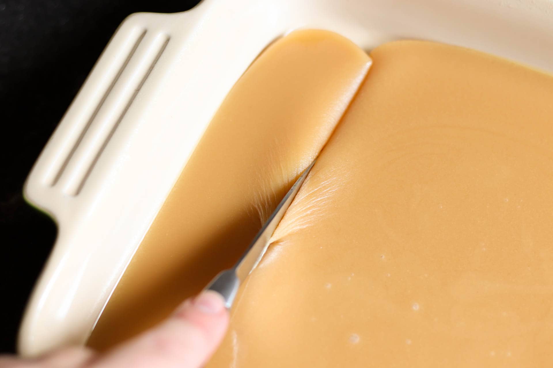 Caramels in a square pan with a knife cutting a row.