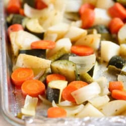 Chopped carrots, zucchini, onions, and potatoes roasted on a foil-lined baking sheet.