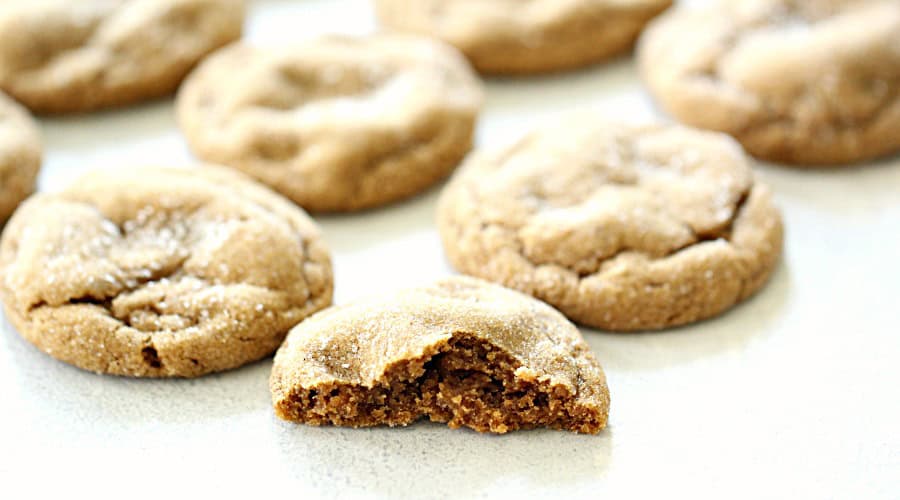 Soft and Chewy Ginger Cookies on a counter with one cookie broken in half to show the inside.