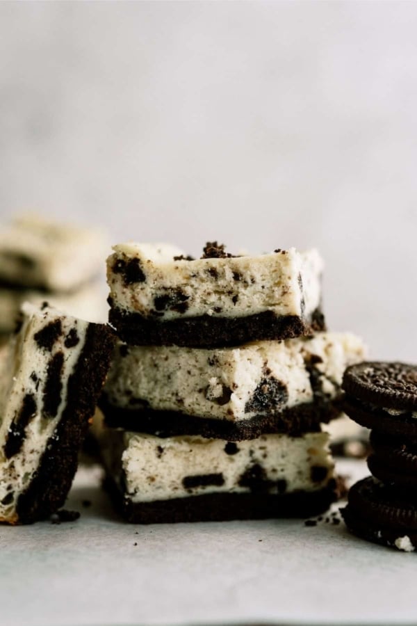 3 Cookies and Cream Cheesecake Bars stacked with one bar leaning against the stack.