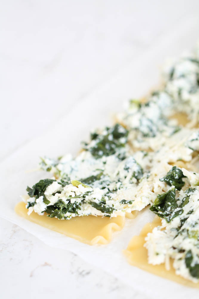 Lasagna noodles with cheese and spinach on them.