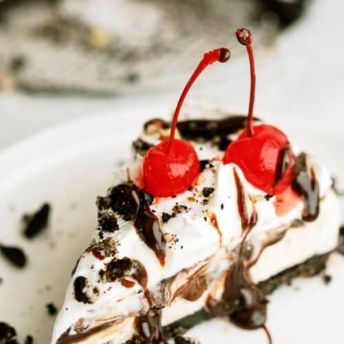 A slice of No Bake Mississippi Mud Ice Cream Pie on a plate topped with two cherries.