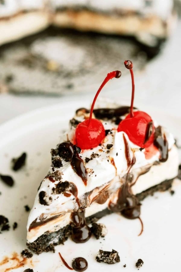 A slice of No Bake Mississippi Mud Ice Cream Pie on a plate topped with two cherries.