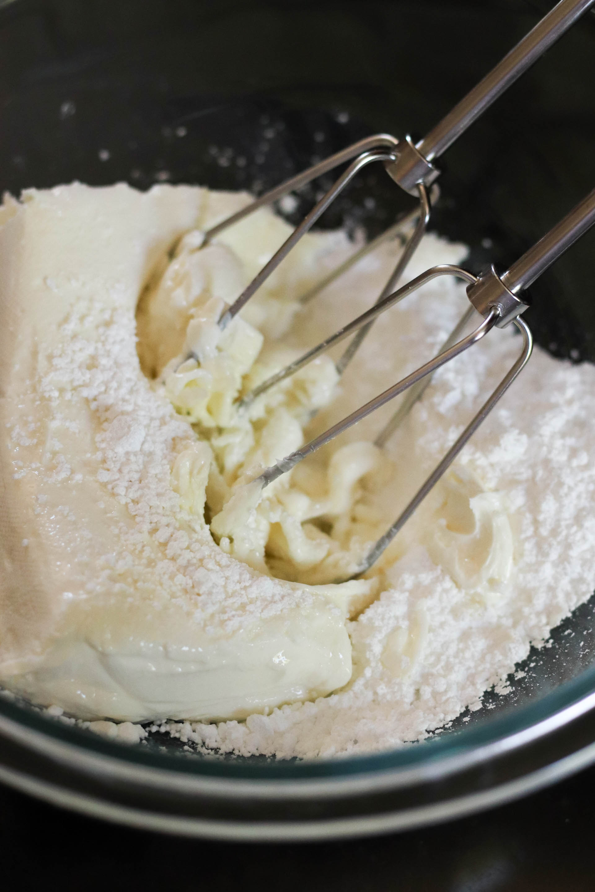 Creaming together cream cheese and powdered sugar in a bowl