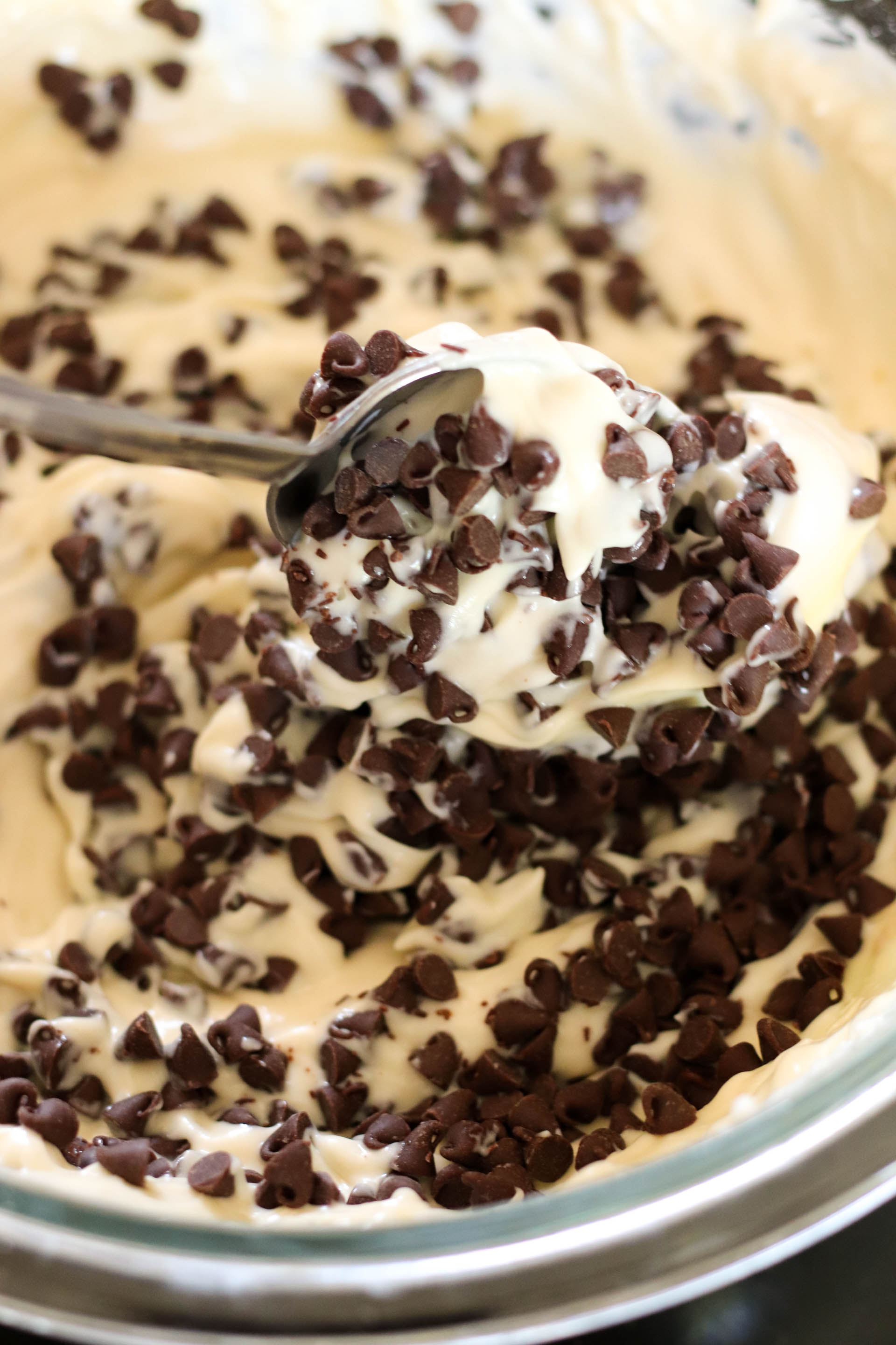 Mixing in mini chocolate chips with a spoon.