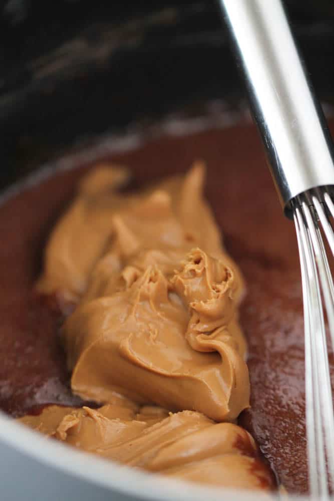 Peanut butter added to saucepan with chocolate and whisk.