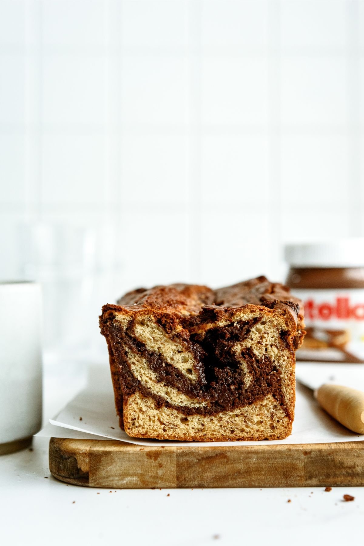 Nutella Banana Bread on a cutting board with Nutella in the background