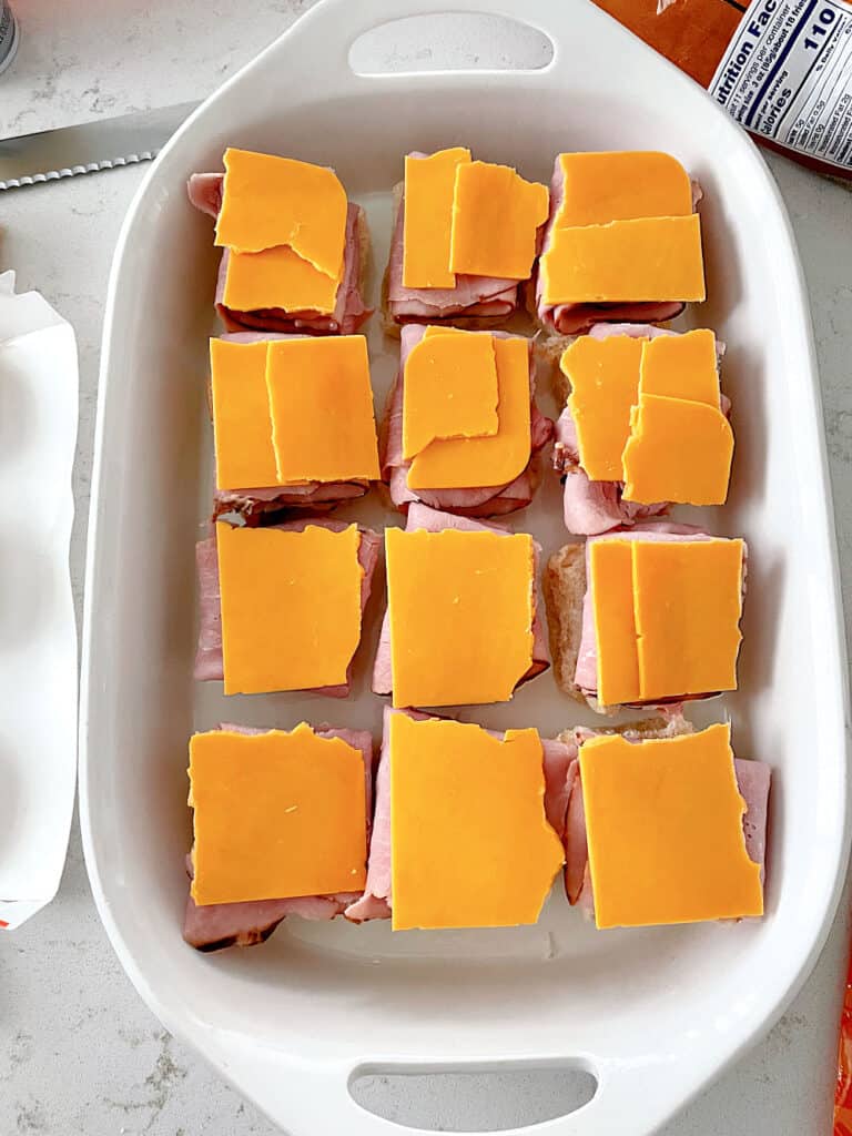 Ham and Cheese layered on top of buns in a baking dish.
