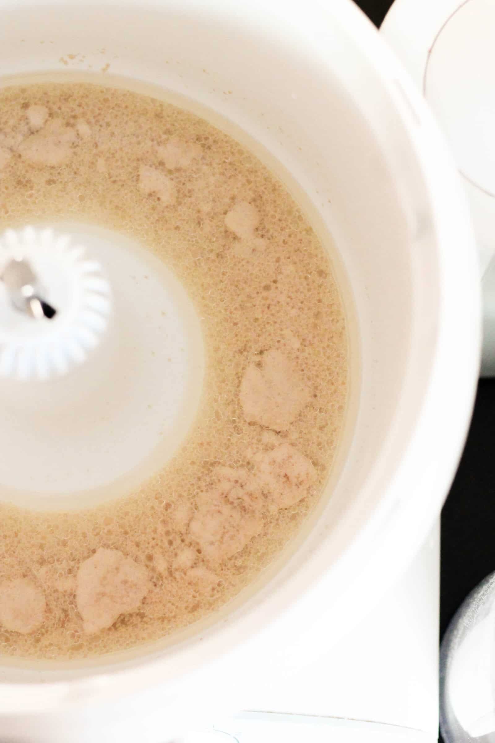 yeast, water and sugar in the bottom of a mixing bowl