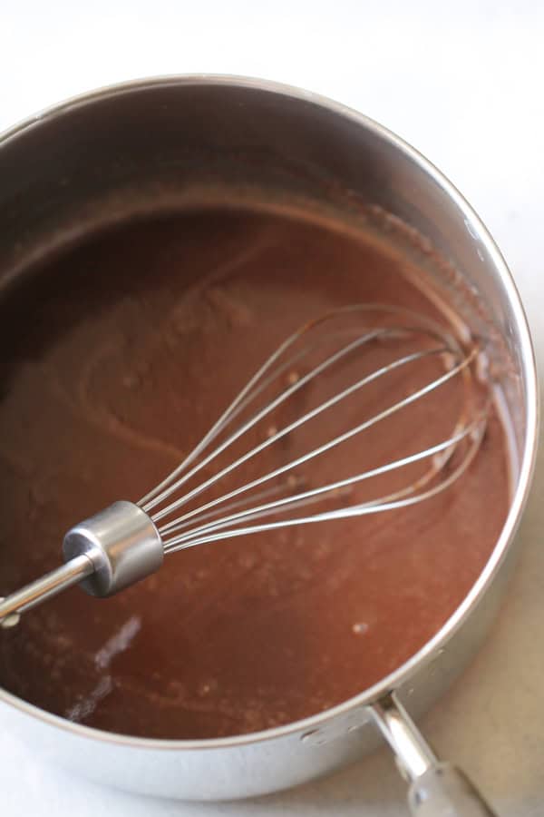 Chocolate sauce in a sauce pan with a whisk.