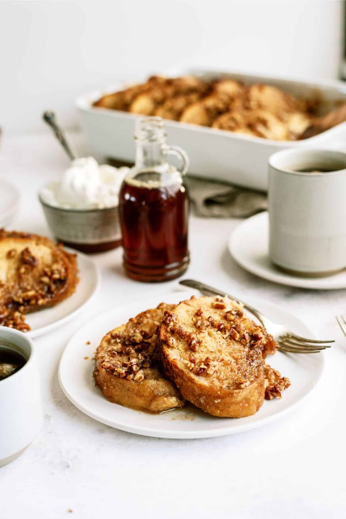 2 slices of Overnight Praline Pecan French Toast Bake on a plate with syrup