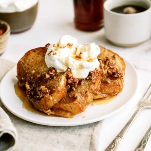 A slice of Overnight Pecan Praline Baked French Toast on a plate with whipped cream.