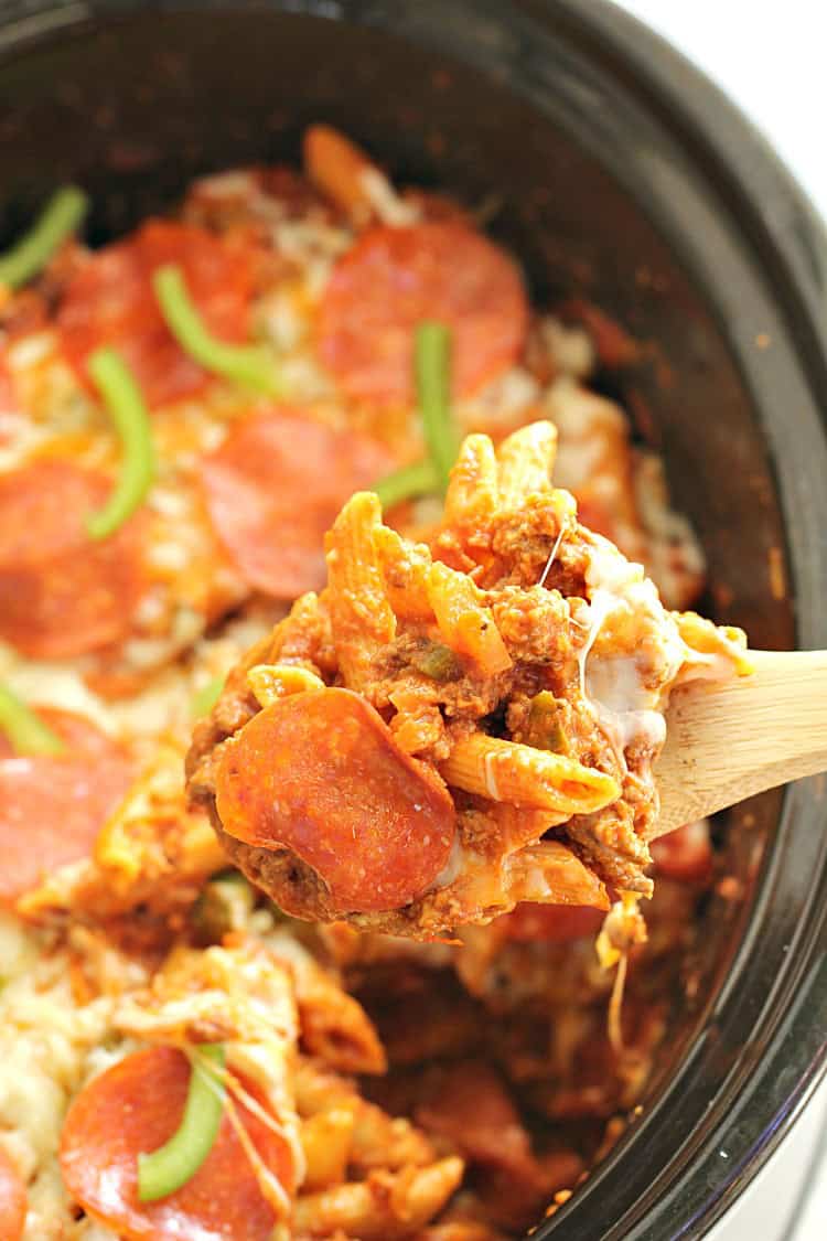 Slow Cooker Pizza Pasta Bake in a slow cooker with a wooden spoon