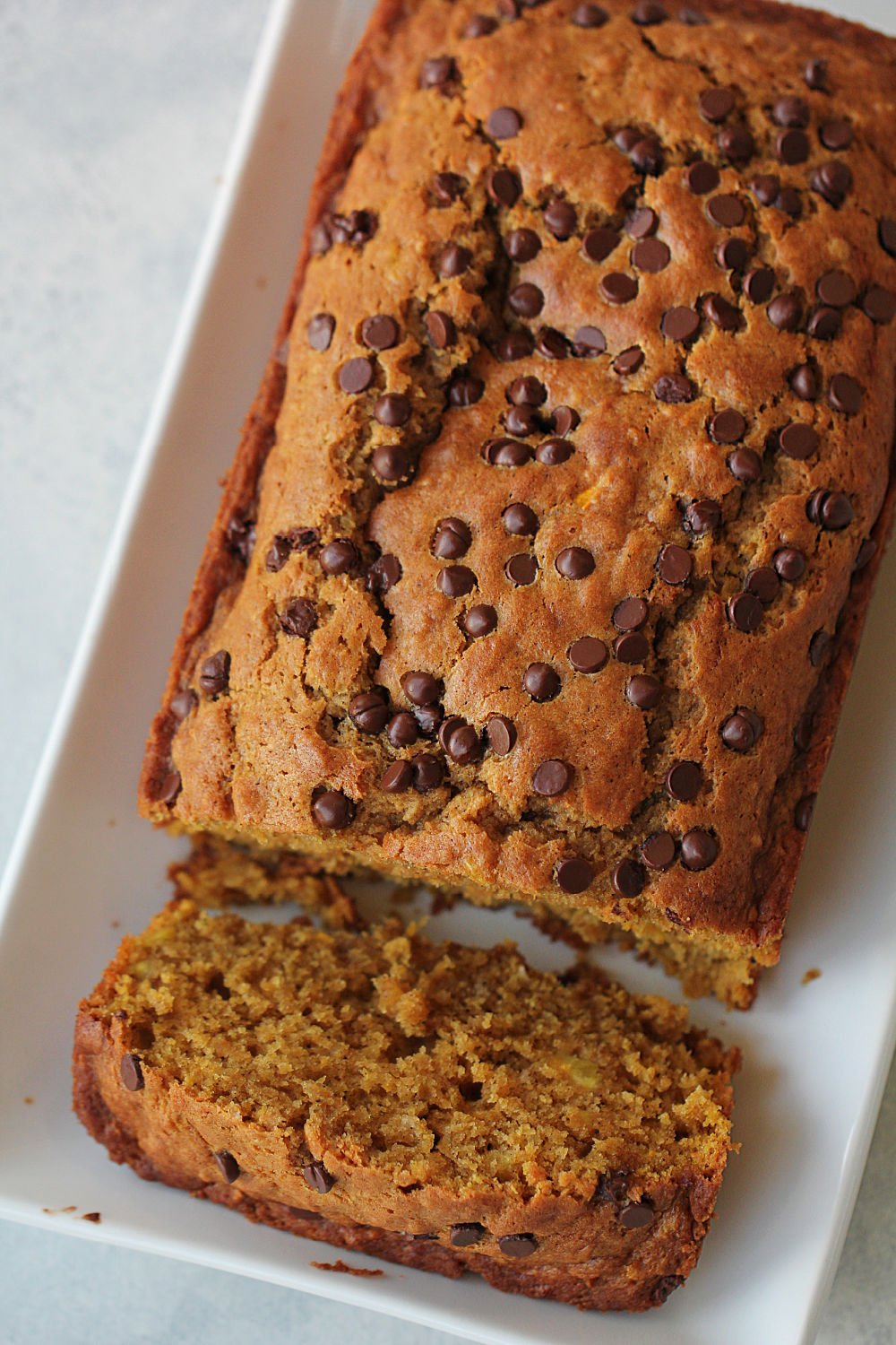 Pumpkin Zucchini Bread on a white serving tray with one slice cut from the loaf