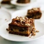 Slice of snickers cake gooey caramel chocolate cake on a plate.