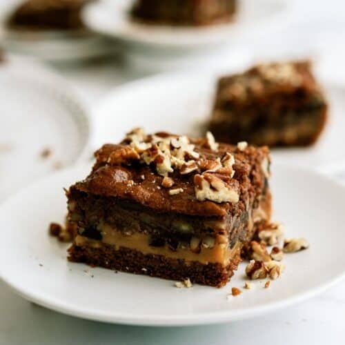 Slice of snickers cake gooey caramel chocolate cake on a plate.