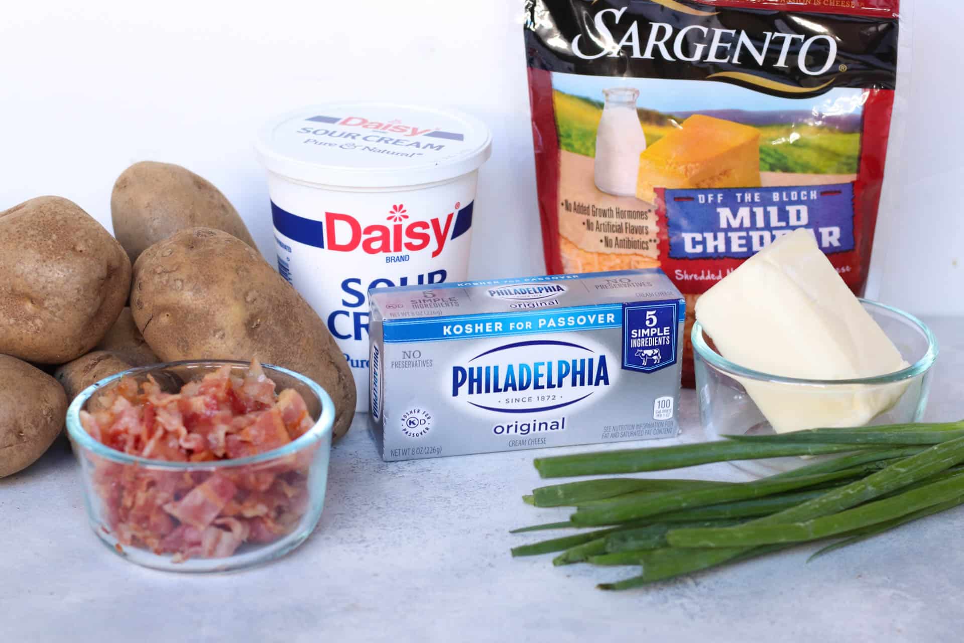 Ingredients for this recipe including potatoes, bacon, sour cream, cream cheese, butter, green onions, cheddar cheese