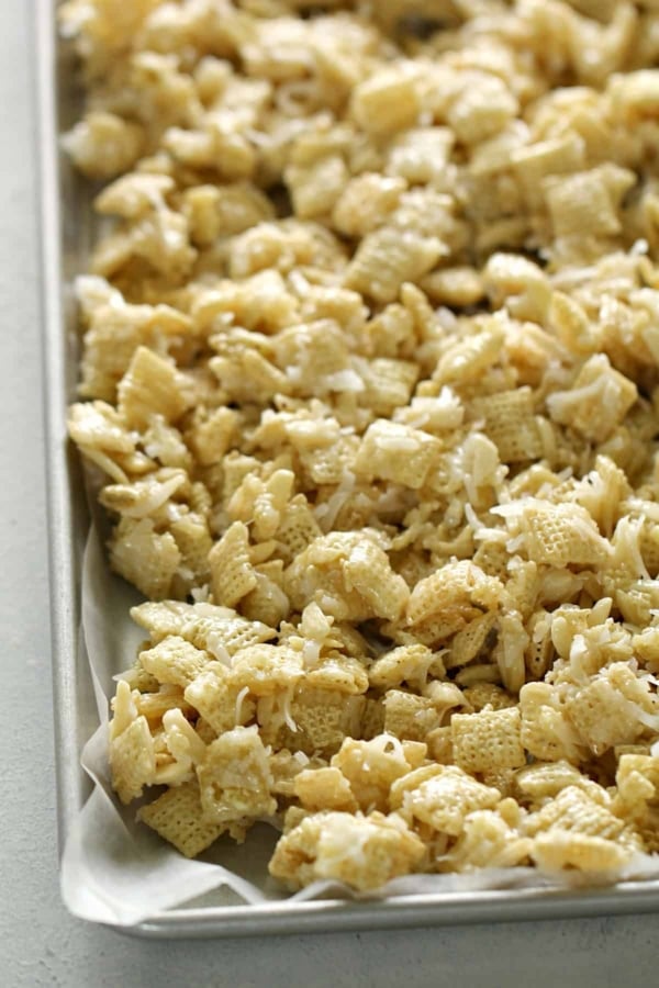 A baking sheet filled with pieces of golden, crisp cereal coated with a seasoning mixture.
