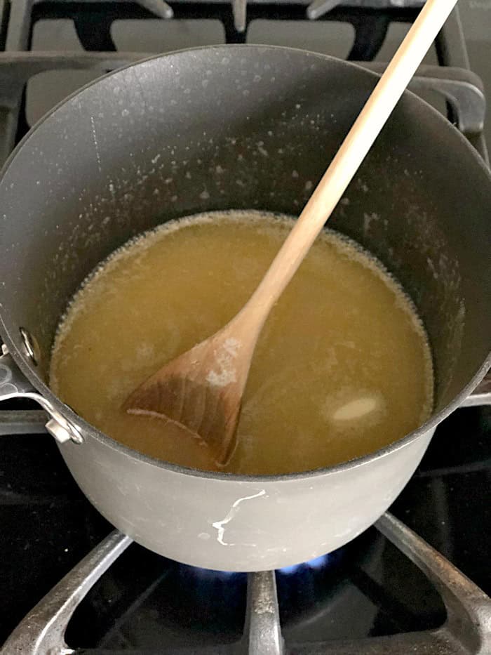 A pot on the stove with the almond mixture in it with a wooden spoon.