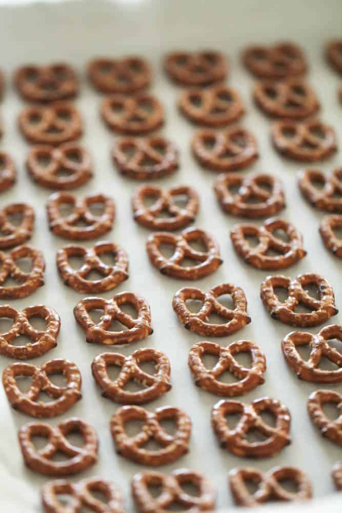 Pretzel twists lined up in rows on a baking sheet lined with parchment paper.