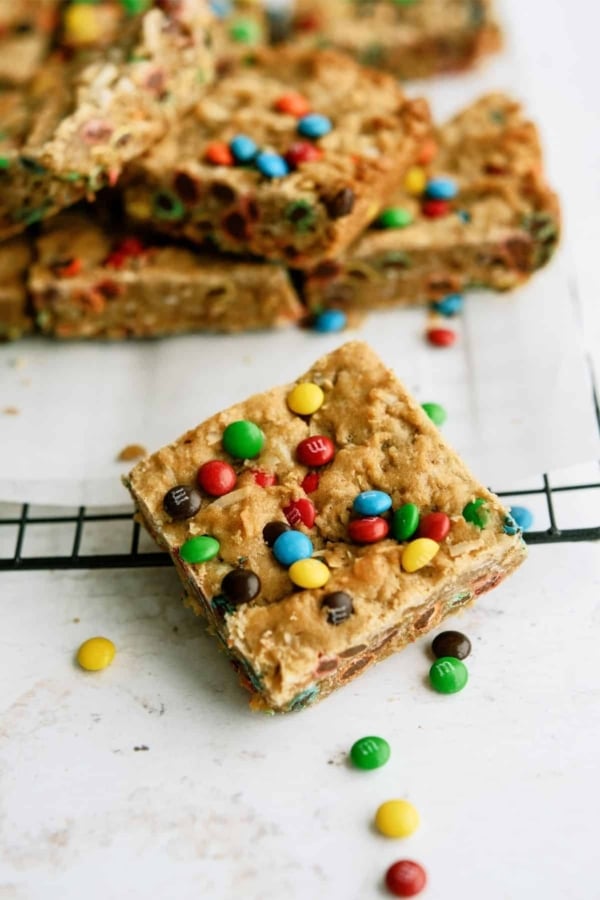 M&M Samoa Blondies cut into squares with one blondie in front surrounded by mini m&m's.