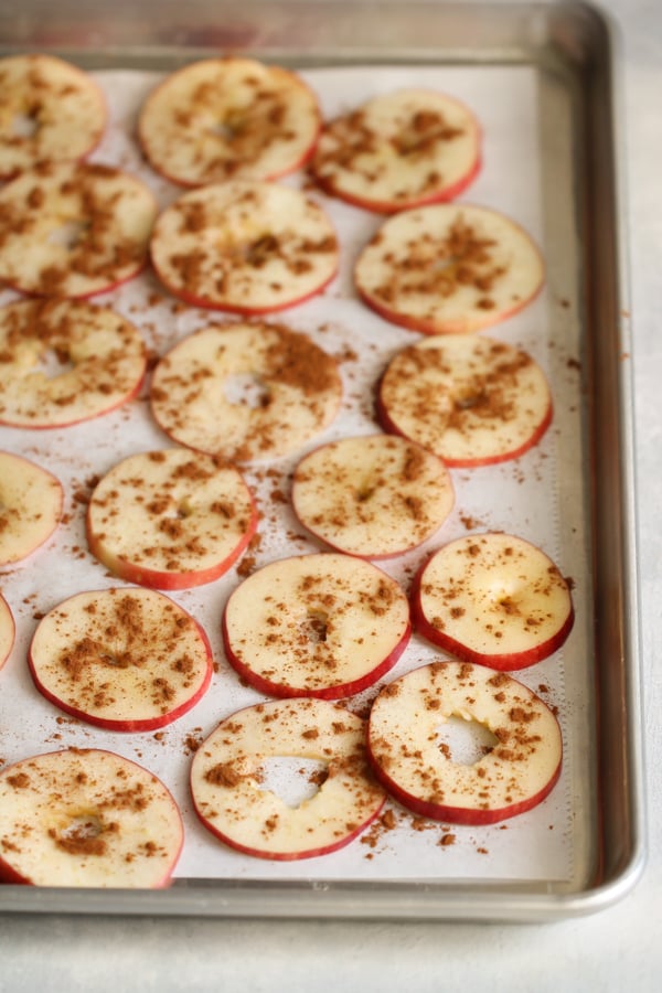 Fresh sliced apples sprinkled with cinnamon on a baking sheet