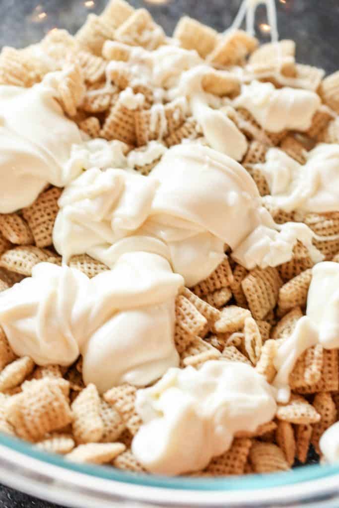 Dropping melted white chocolate on a bowl of Rice Chex.