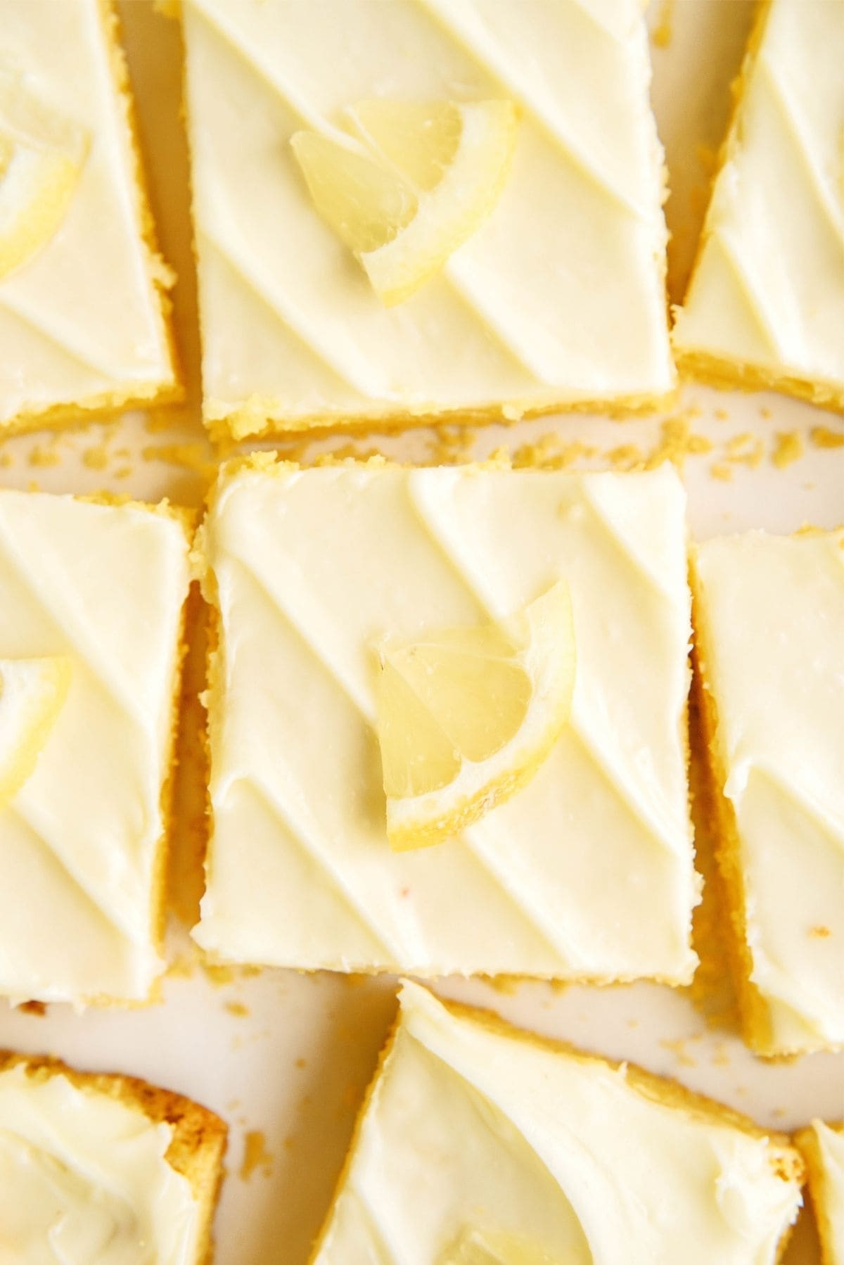 Sliced Frosted Gooey Lemon Bars garnished with Lemons