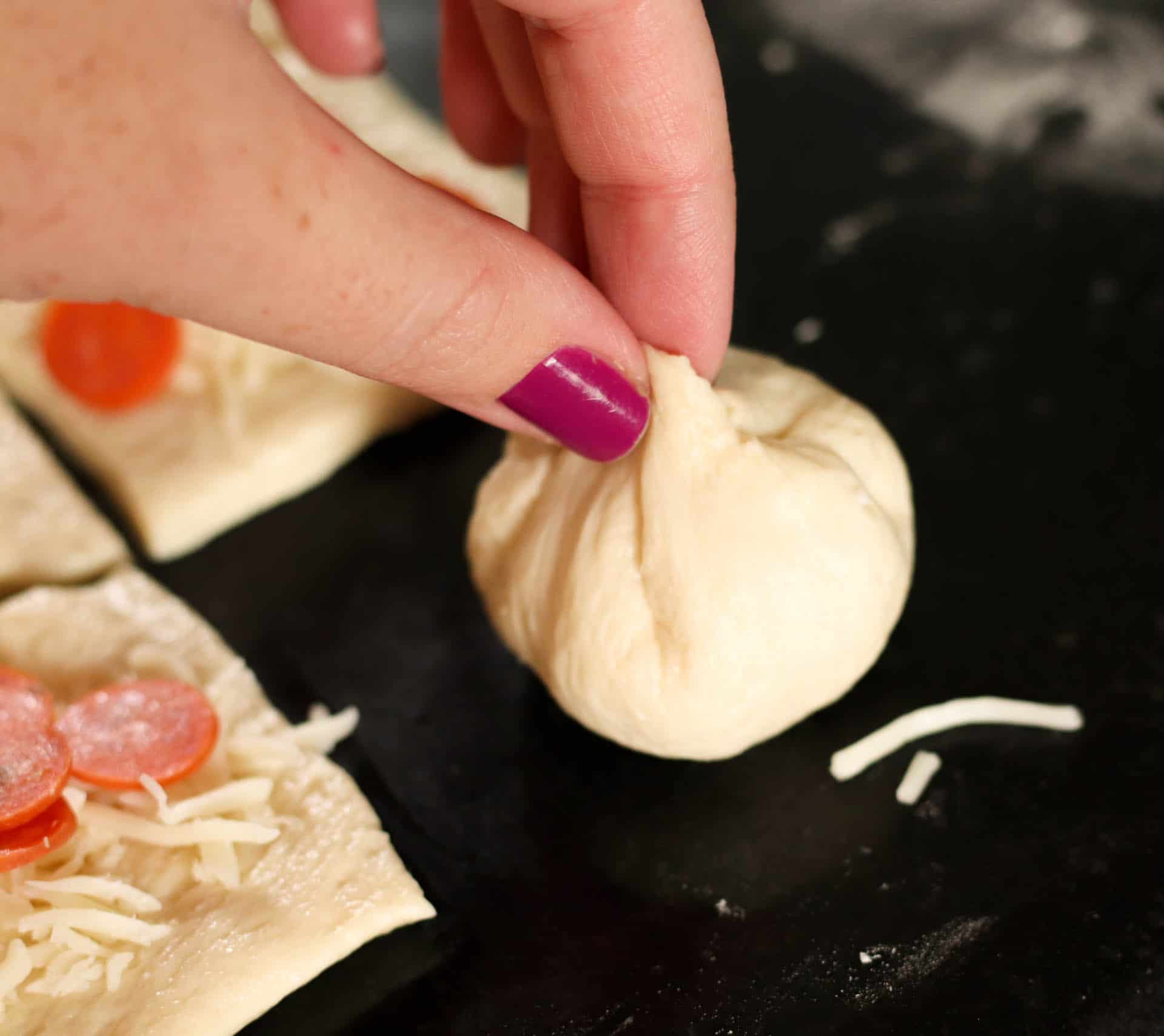 Pinching closed an unbaked Stuffed Pizza Roll