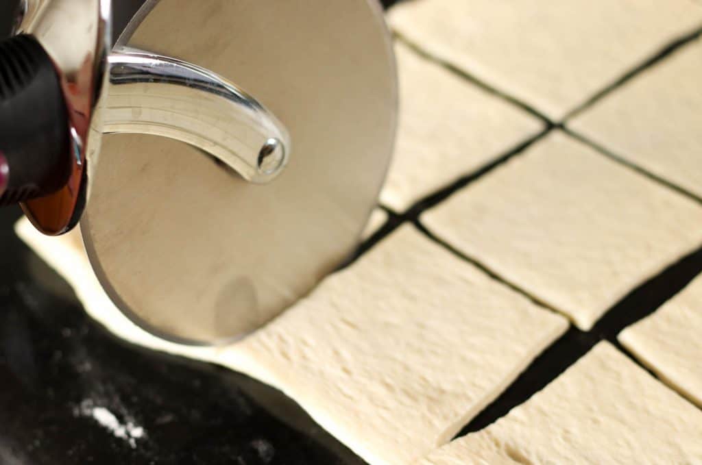 Cutting pizza dough into a square.