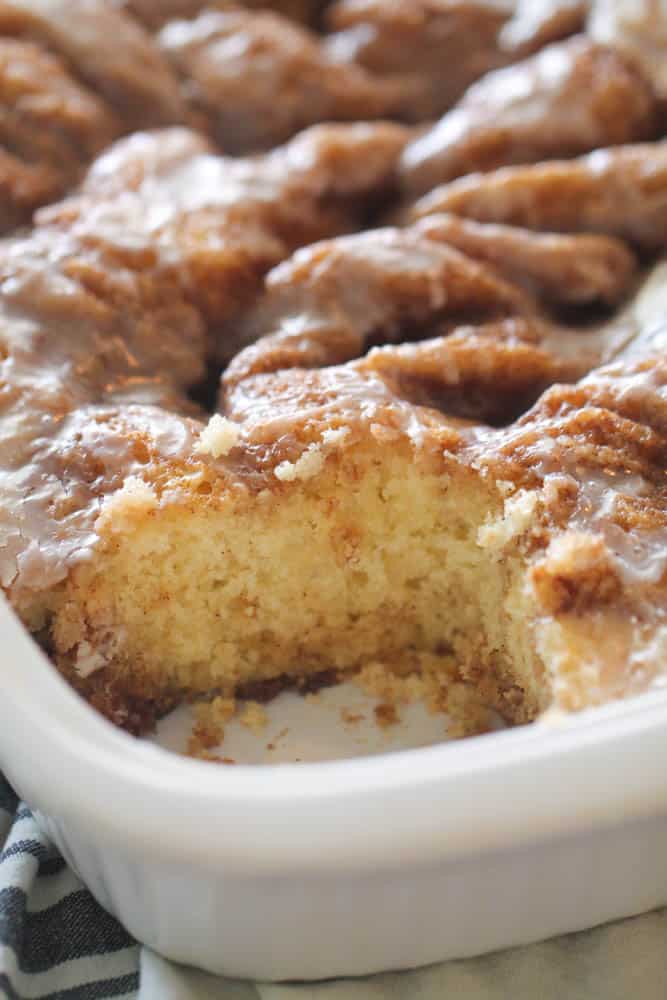 Cinnabon Cinnamon Roll Cake in cake pan with one corner slice missing