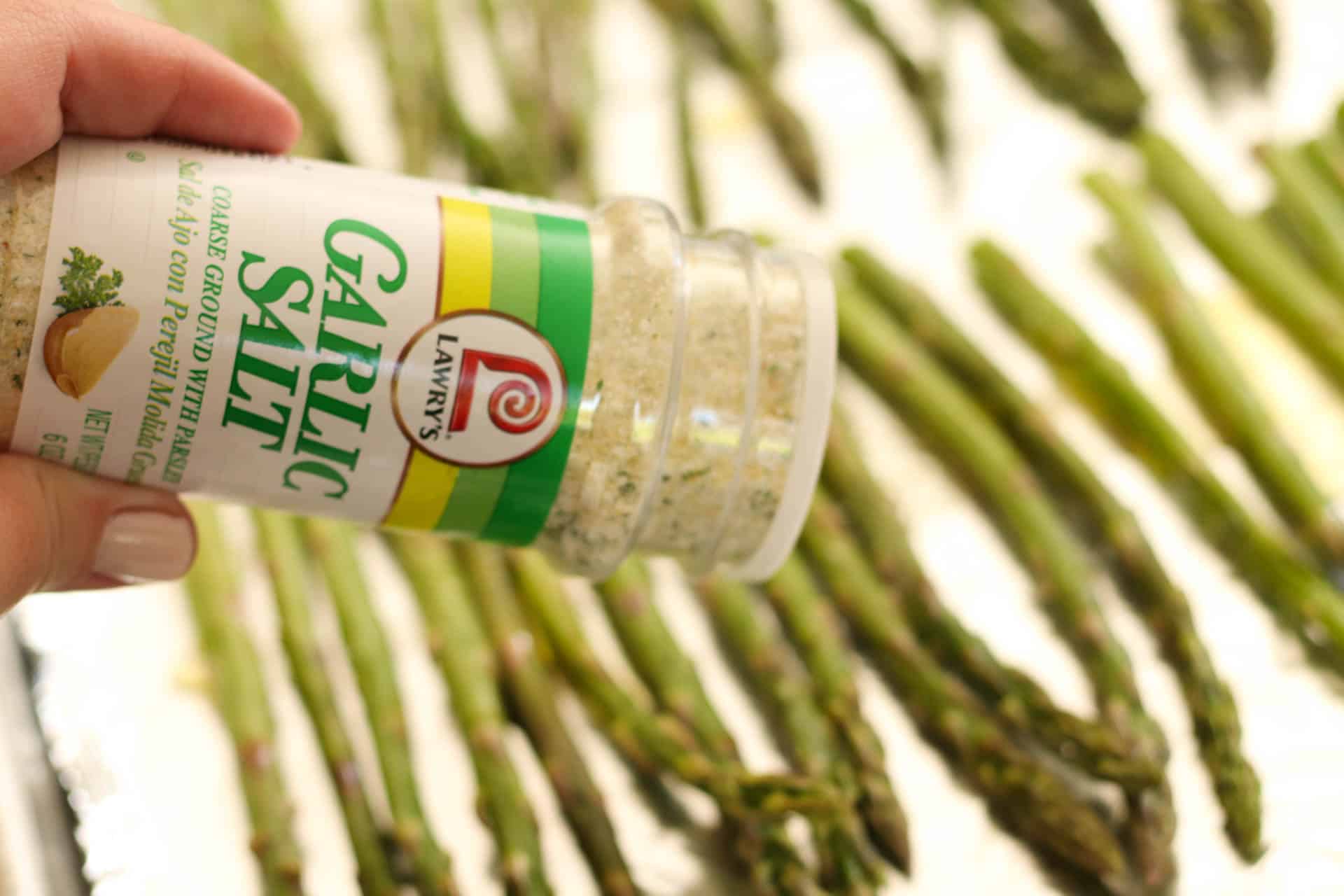 Sprinkling garlic salt on top of asparagus