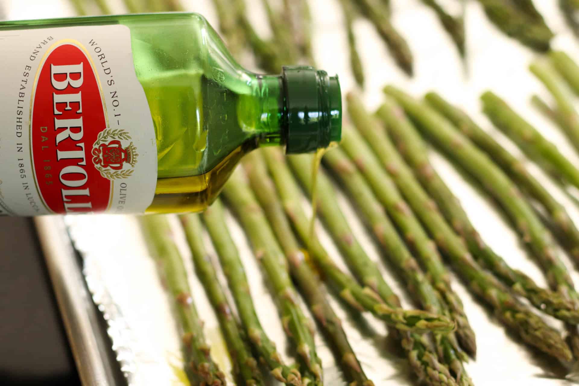 Drizzling olive oil on top of asparagus