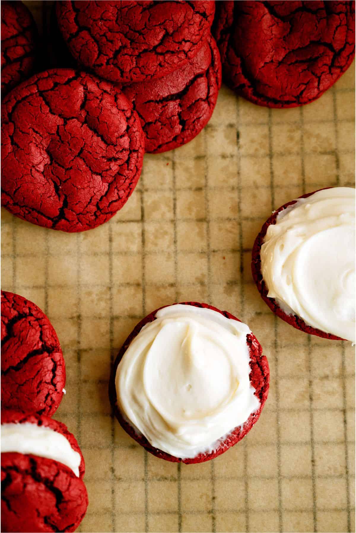 Red Velvet cookies on a cooling rack with one made into a Whoopie pie and one with just frosting on top.