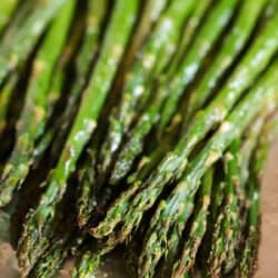 Close-up of roasted asparagus spears on a sheet of aluminum foil.