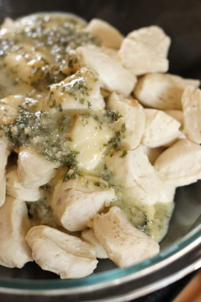 Sauce poured on top of cut biscuits in mixing bowl.