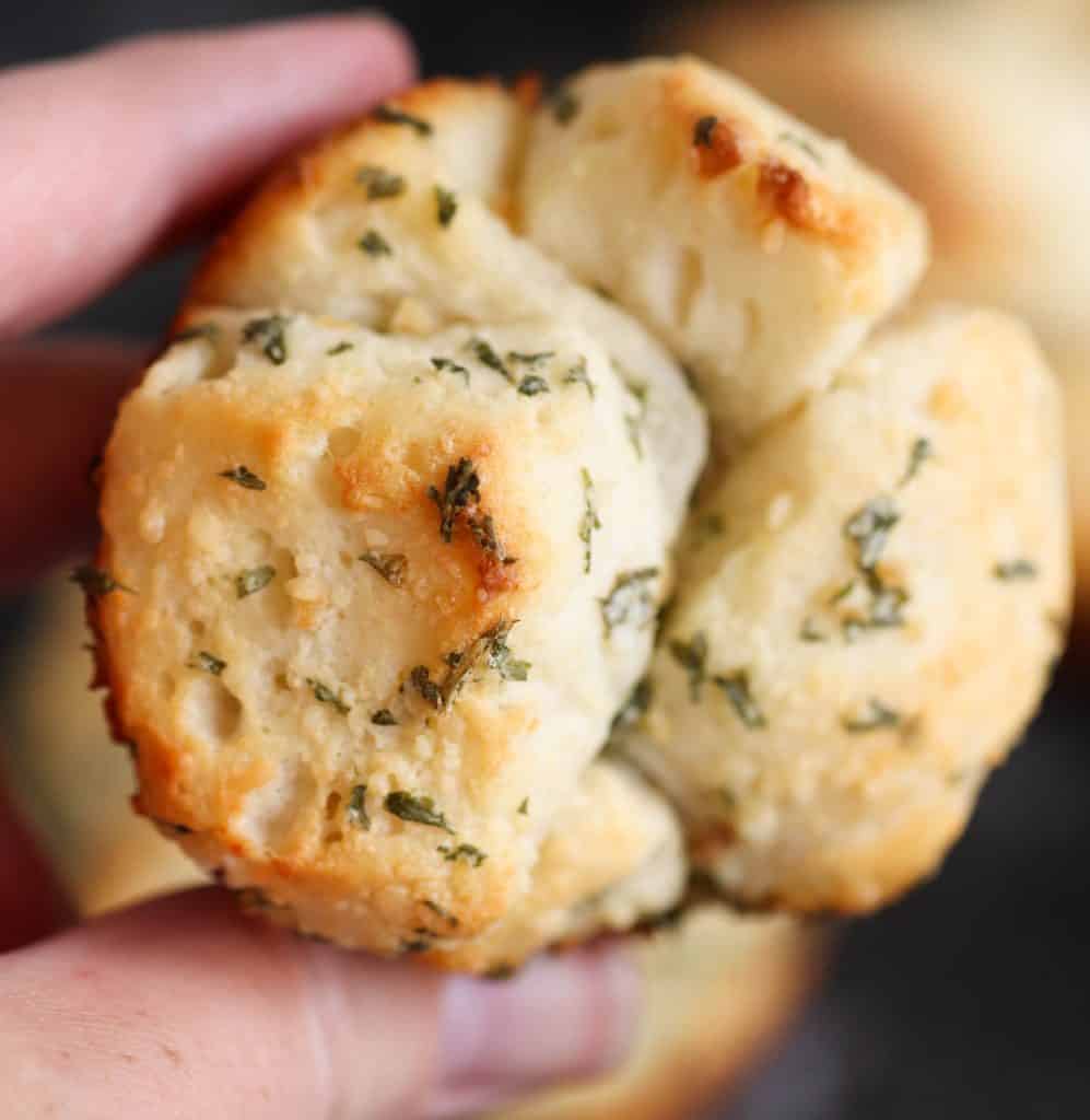 A hand holding one Mini Garlic Monkey Bread.