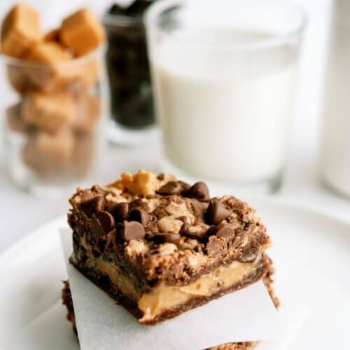 2 Better Than Anything Brownies on a white plate with a glass of milk in the background.