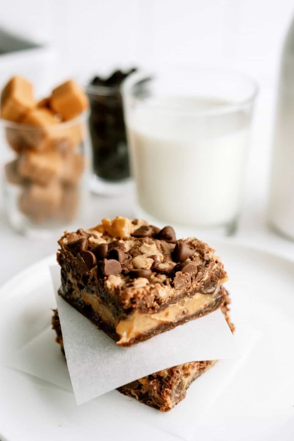 2 Better Than Anything Brownies on a white plate with a glass of milk in the background.