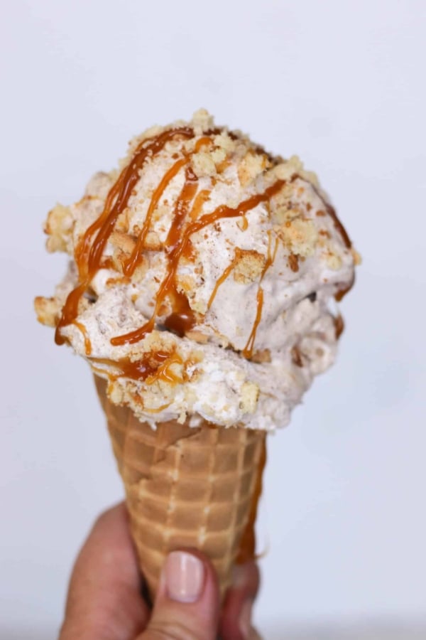 Homemade Caramel Snickerdoodle Ice cream in a sugar cone drizzled with caramel sauce.
