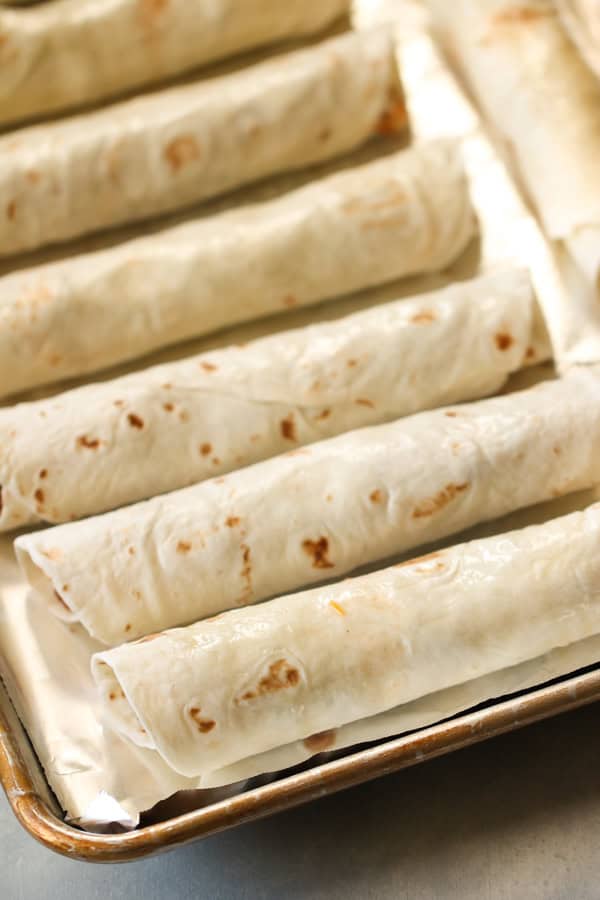 Unbaked Beef Taquitos on a baking sheet covered with foil
