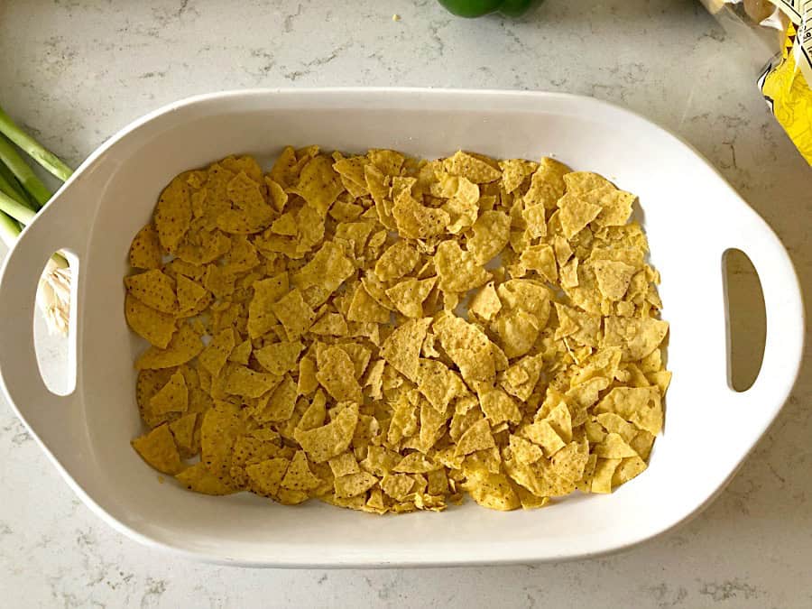 Crushed tortilla chips in a white casserole dish