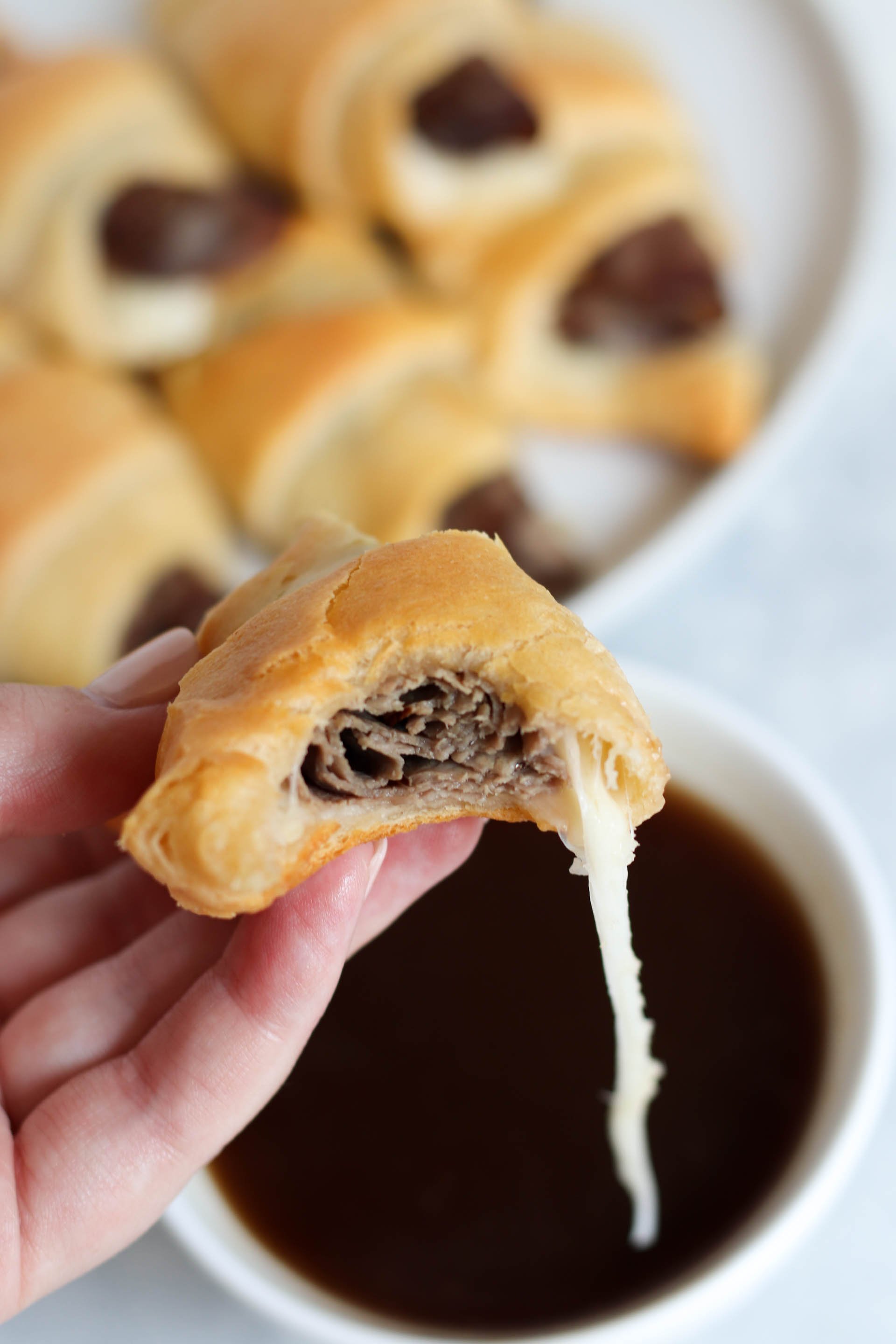 cooked french dip crescent dipped in Au Jus Gravy with stretchy cheese