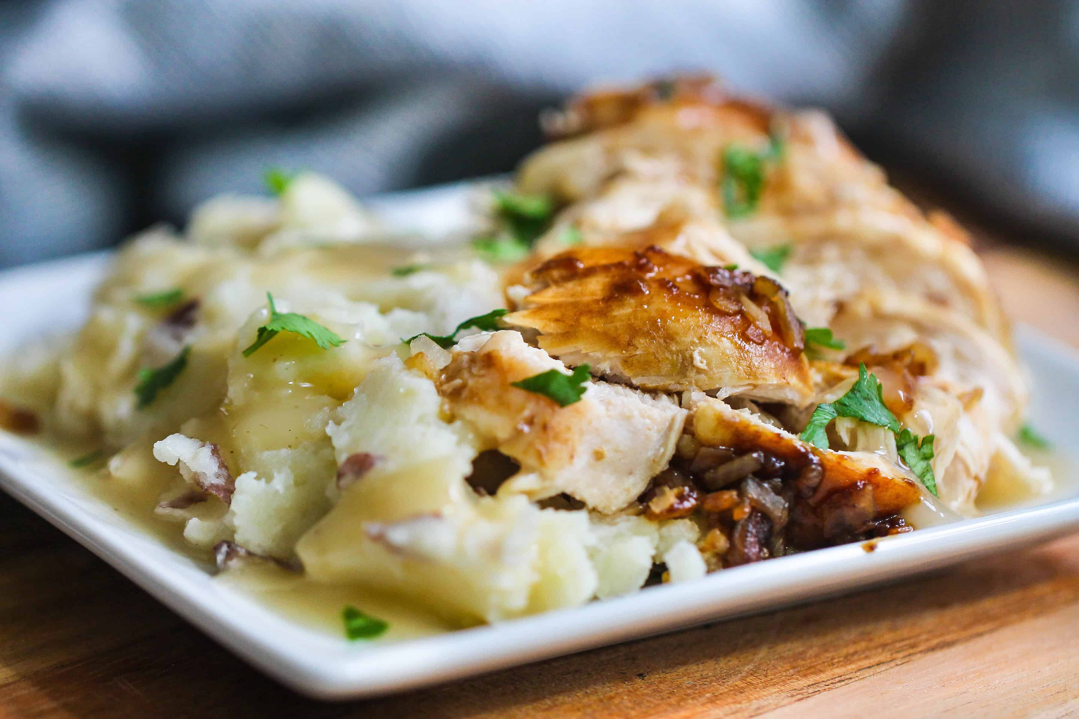 Slow cooker turkey breast sliced on a plate with mashed potatoes.