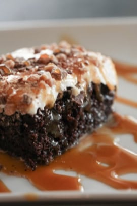 A slice of Chocolate Caramel Toffee Crunch Cake on a plate drizzled with caramel sauce.